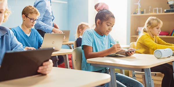 Students sitting at their desks with tablets and laptops