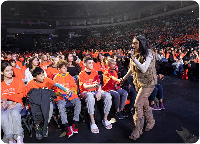 Students high fiving live performer at the 2024 Youth Empowerment Gathering